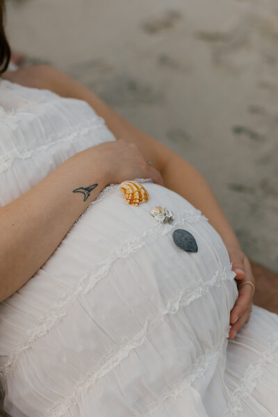 A maternity session as the sun sets, warm taupe and white dress in the sand