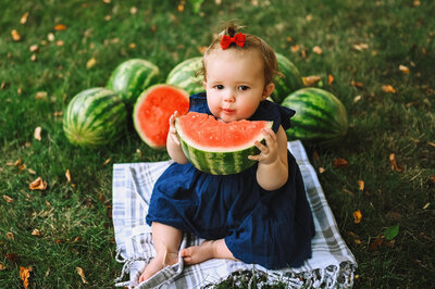 A baby chews with a mouth full of watermelon for her Iowa Milestone Photos
