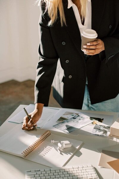 standing-woman-writes-in-notepad-at-desk