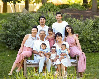 extended family portrait sitting on park bench wearing pink and white