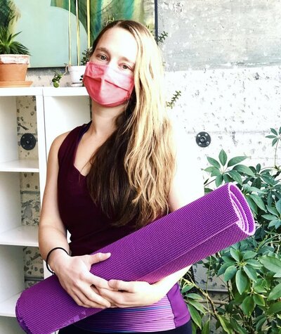 masked woman holding yoga mat