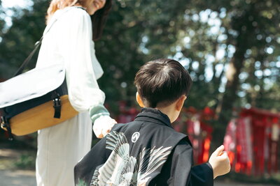 ５才七五三の男の子がママと手を繋ぎ神社へお詣りしている写真