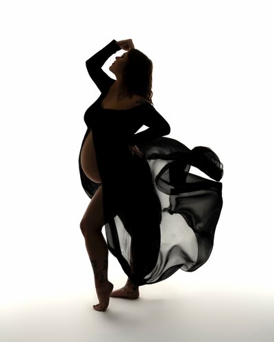 Silhouetted figure in a flowing black fabric captured mid-motion