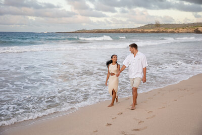 Maui Wedding Photographer captures couple walking hand in hand by water after sunset beach wedding