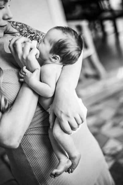 A tiny baby lies in his crib on his tummy wearing his newborn size diaper.