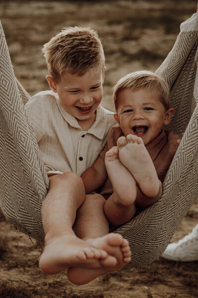 Broertjes lachen in hangmat tijdens familie fotoshoot