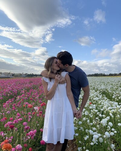 man and woman kissing in field surrounded by flowers