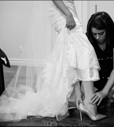 Casey McKenna, founder of Most Valuable Bridesmaid supporting bride to put on her shoes as part of day-of coordination service in New York