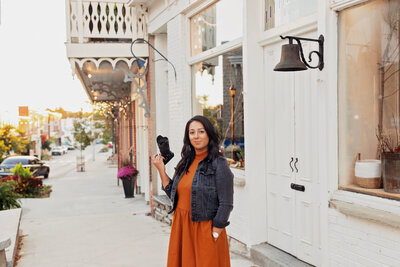 Farrah Sanjari, Ottawa mini sessions photographer, standing with camera in downtown Almonte. 