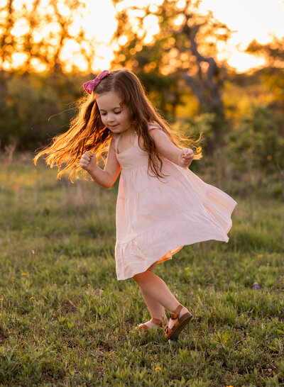 little girl twirling in golden sunlight