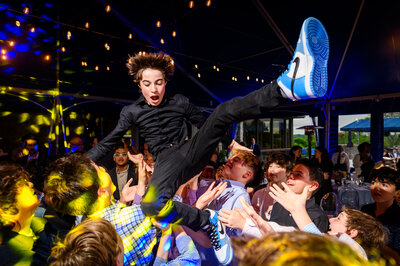 Pure joy and excitement as the Bar Mitzvah boy is launched into the air by his friends, a memorable highlight of his celebration