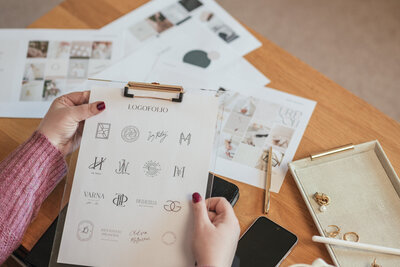 Clipboard with refined logo designs for luxury brand identity projects by Sarah Shuttle.