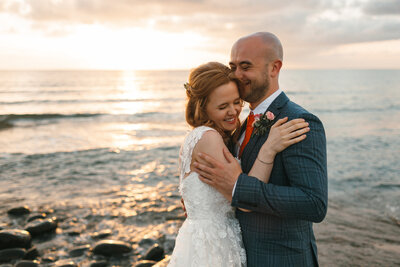 Couple embrace at their intimate wedding at sunset by the sea in Devon