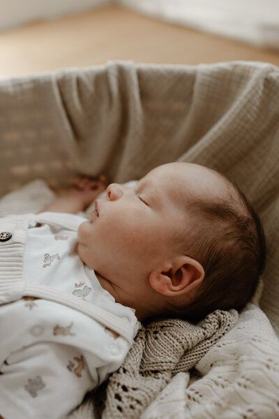 koppel geeft hun pasgeboren baby een kus op het hoofd tijfens een in-home newborn fotoshoot te Bonheiden.