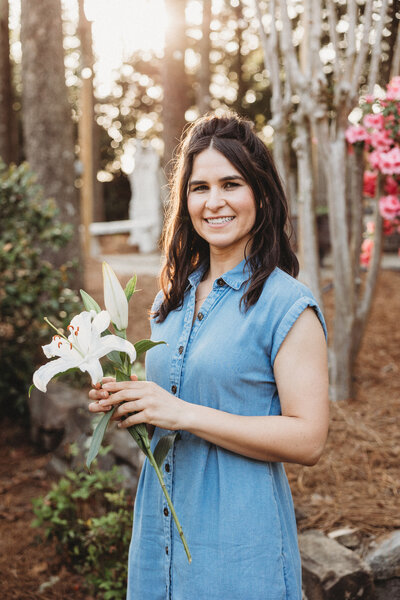 Sarah smiling while holding a white lily flower