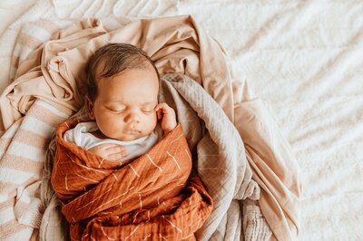 Photo of newborn baby snuggled in a swaddle fast asleep during a newborn photograpy session