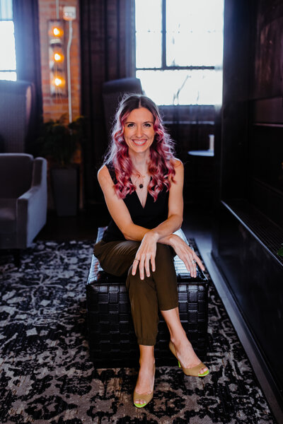 woman sitting on table with legs and arms crossed while smiling