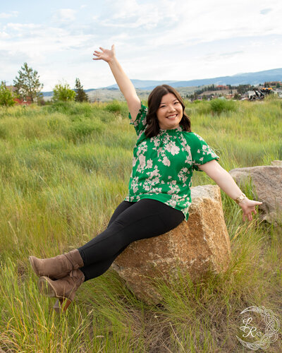 photo of Ashlyn sitting on a rock with her arms spread and legs pointed straight in front of her