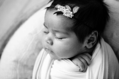 sleeping newborn girl in ivory swaddle and headband