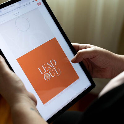 a person holding an ipad looking at the leadout communications logo on isntagram