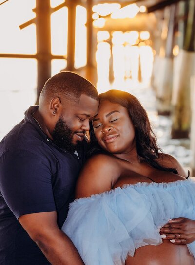 A glowing expectant mother and her husband poses gracefully on the beach, showcasing the essence of maternity photography in a natural setting.