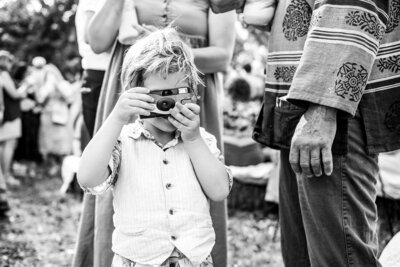 Young child photographing with a toy camera at an outdoor family gathering in Connecticut