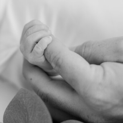 Newborn holding fathers finger