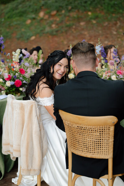bride and groom laughing while sitting at their dinner table during wedding reception
