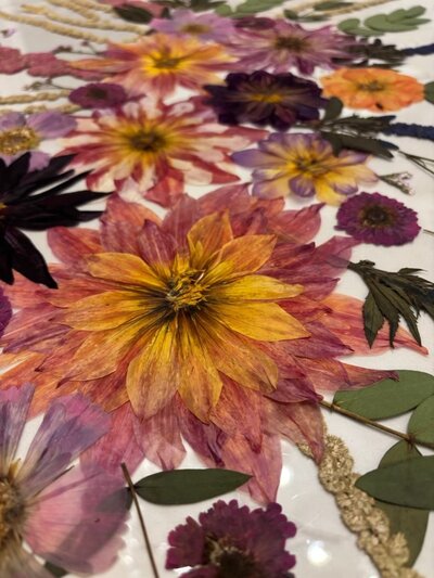 Dried and pressed flowers are preserved in resin, representing bridal bouquet preservation services offered by Dame Designs. 