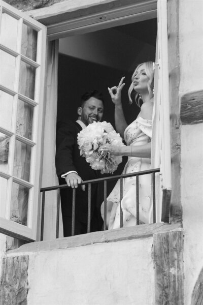 Bride holding up a peace sign and groom smiling back 