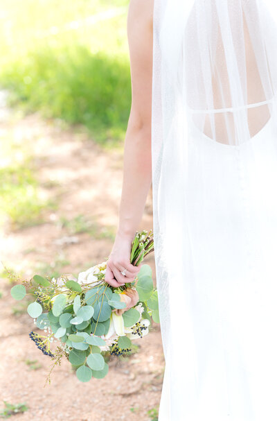Bride walking with her flower bouquet down on her side against her dress