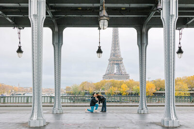Man kneeling and kissing his partner outside the Eiffel Tower just after proposing, captured during a romantic Paris proposal photoshoot.