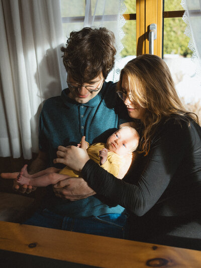 Mutter und Vater sitzen am Tisch mit Baby im Arm