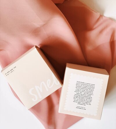 Smelle candle company boxes laying on pink fabric
