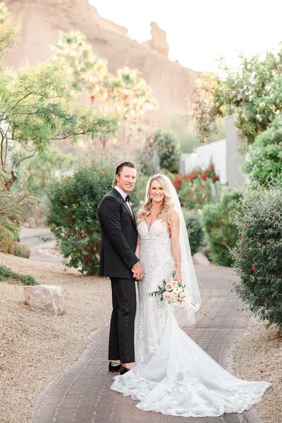 Bride and Groom looking at the camera on a path at the Sanctuary in Scottsdale with the mountain behind them