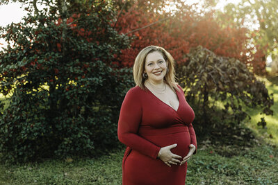pregnant woman in red dress outdoors by philadelphia maternity photographer