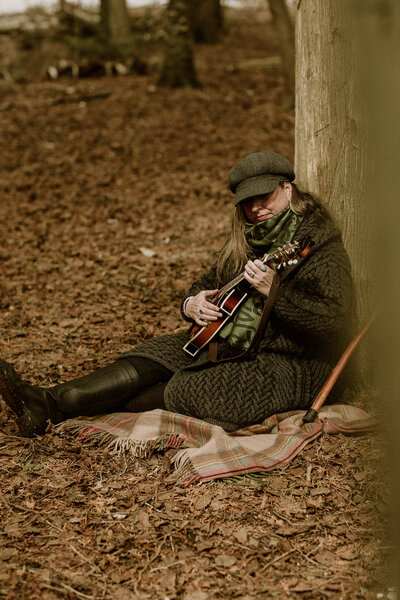 woman playing guitar in forest 
