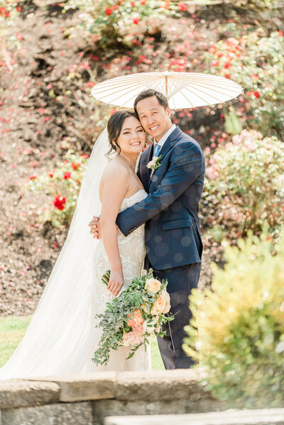 bride and groom holding umbrella together in the sun at Lord Hills Farm in Seattle, Washington. Captured by Lessie, Top Seatte Wedding Photography..