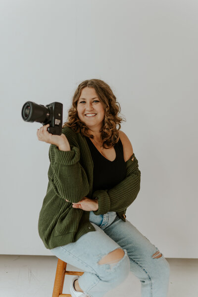 Kayla Marie, Midwest wedding photographer, smiling with camera, capturing authentic love stories.