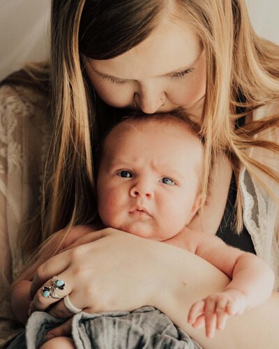 Momma and baby, baby looking at camera and momma kissing babies head