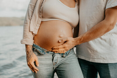 Maternity photos by the water in Indianapolis. Dad holding moms belly