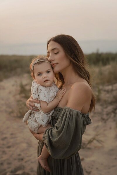Mother holding baby at golden hour by photographers in West Michigan