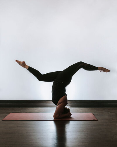 Black and white image of Alex Paige in a yoga pose on the ground next to a pool under an arched wall