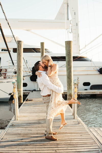 An engaged couple kissing on the dock