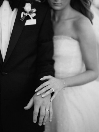 Close-up of a bride and groom’s hands showing their wedding rings, symbolizing love and commitment.