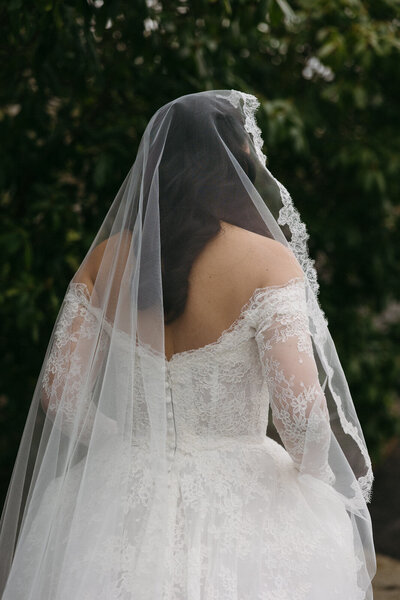 Bride walking through the gardens at Rosecliff Mansion in Newport, Rhode Island with her lace veil and dress trailing behind her, photographed by Andrea-Marie Photography