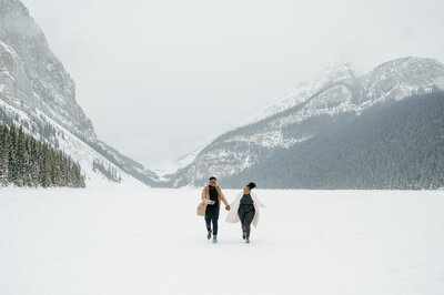 Couple running in winter proposal in Lake Louise