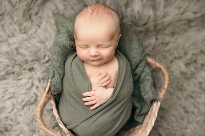 baby boy in green wrap in basket in portland photography  studio