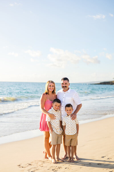 family and two boys smilin gat the camera on the beach at Hapuna resort