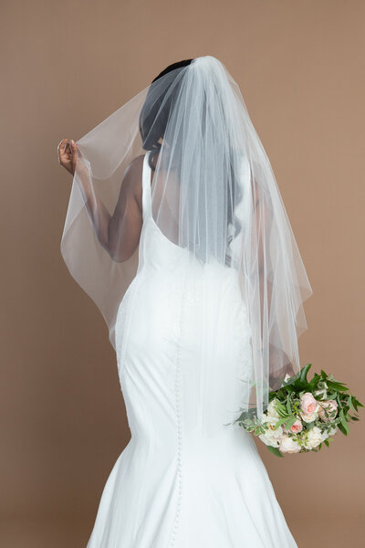 Bride wearing a two layered fingertip length veil and holding a white and blush bouquet